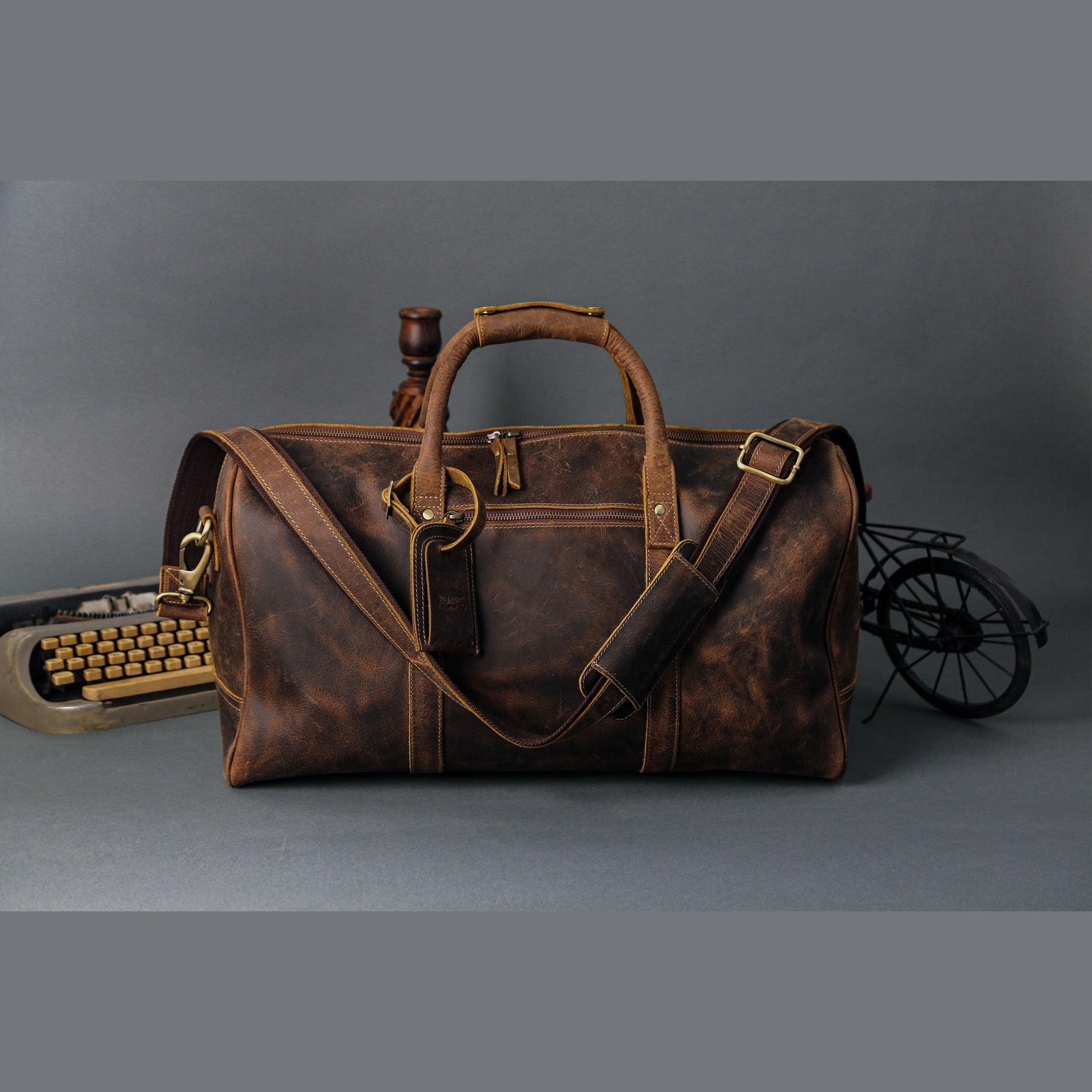 Vintage brown leather duffel bag with grab handles and shoulder strap