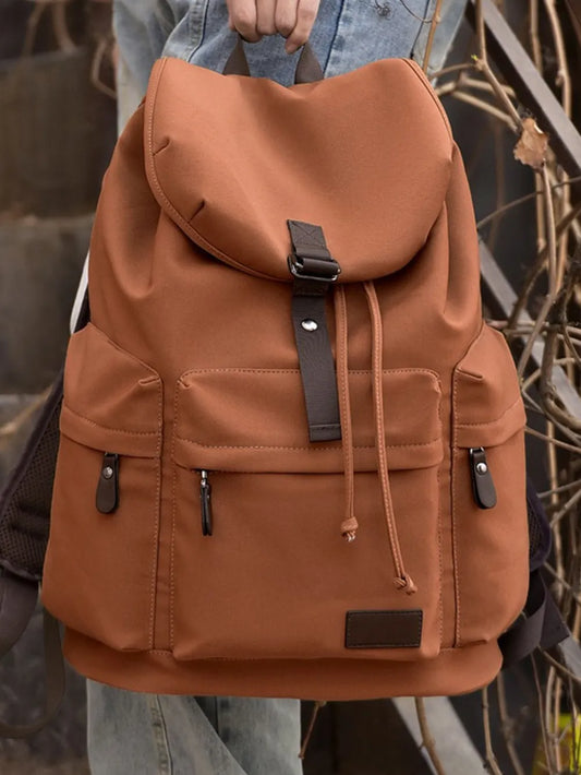 Large brown canvas backpack with flap closure, multiple front pockets, and adjustable shoulder straps