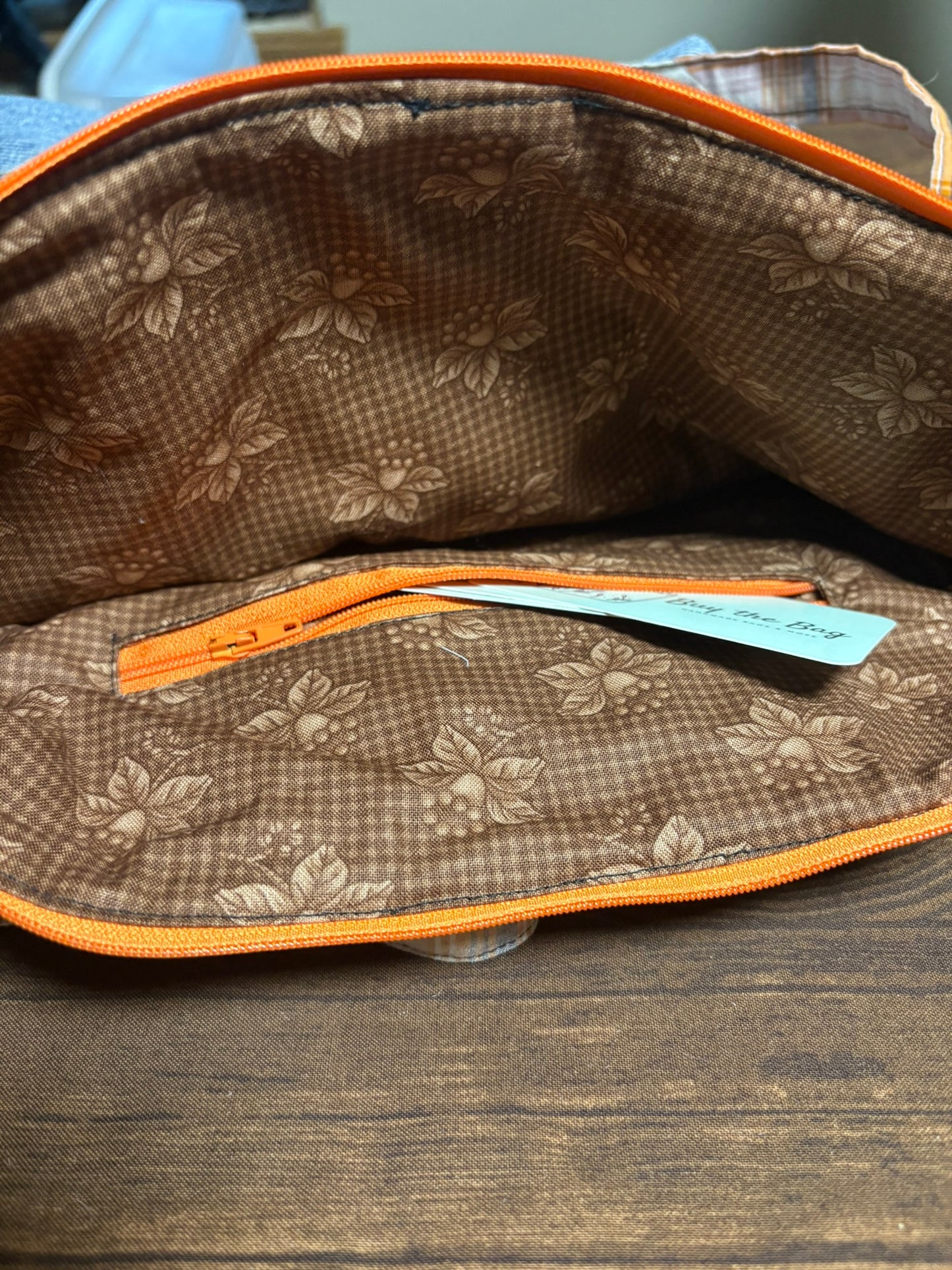 Floral-patterned pouch with orange zipper on a wooden surface