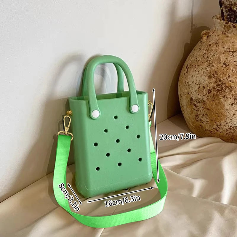Green handbag with measurements on a beige surface