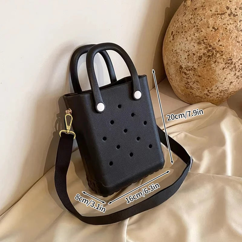 Black handbag with measurements on a beige surface