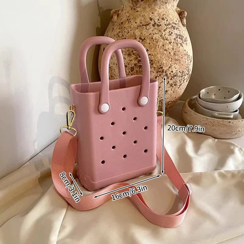 Pink handbag with measurements on a neutral background